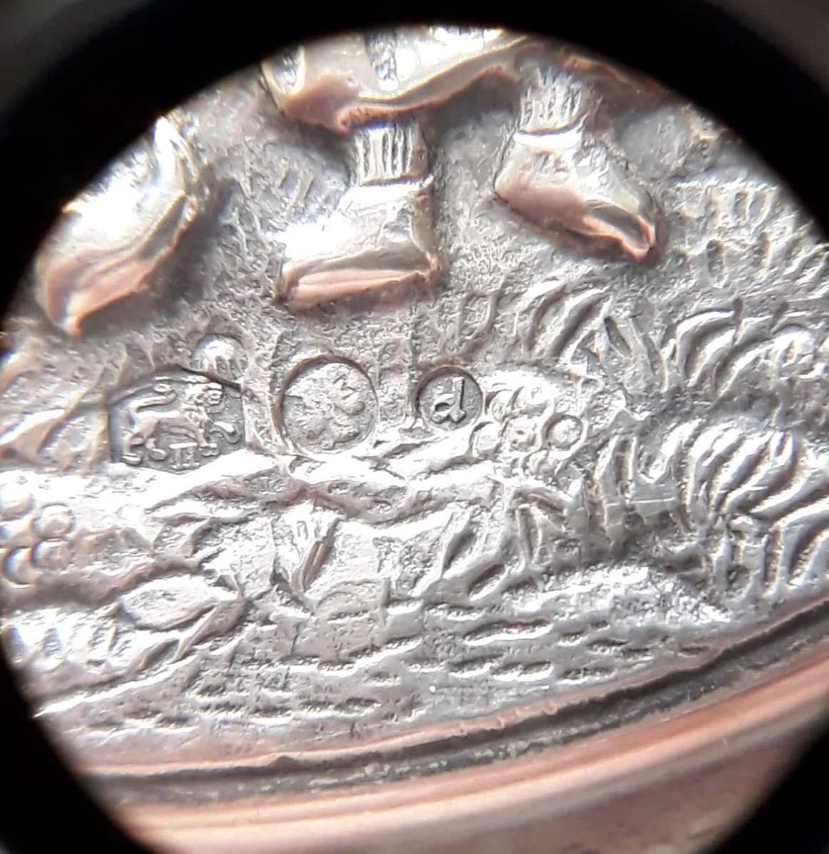 Mein ungeübtes Auge sieht einen nach rechts schreitenden Löwen, darunter römisch II, dann einen nach links schauenden Minervakopf (?) und den Buchstaben M, ganz rechts ein kleines d.